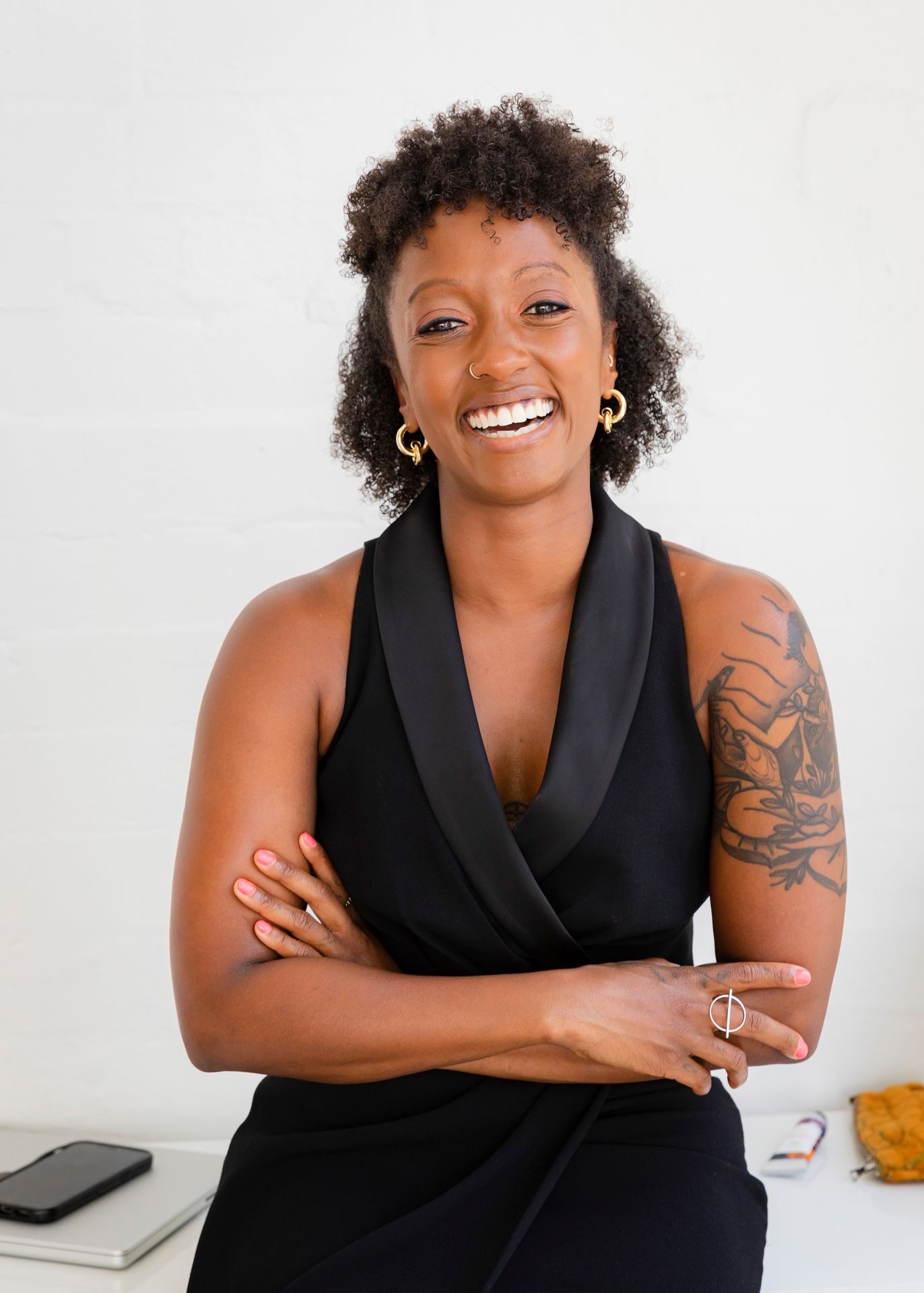 Black woman CEO wearing black dress crossed arms with tattoo